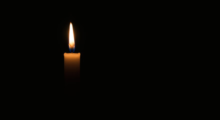 Fototapeta premium A solitary candle flame burns brightly against a deep black background, casting a soft, warm glow and evoking feelings of peace, reflection, and quiet remembrance