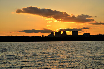 Silhouette of a city district at sunset. A Kyiv neighborhood in the rays of the setting sun. View from the left side of the Dnieper.