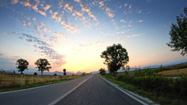 POV vehicle drive on local road, agricultural landscape, summer evening