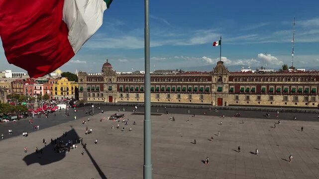 Crane-up shot revealing the Mexican flag in the foreground with the National Palace and Mount Tlaloc in the background at Zocalo square in Mexico City, Mexico