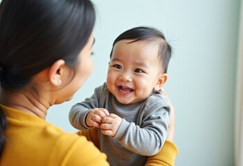 An elderly Asian woman, a grandmother, holds her little grandson in her arms. The grandmother and grandson are having fun and playing