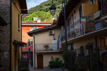 Charming streets of a small Italian village surrounded by lush green hills in the afternoon sunlight with colorful buildings and balconies