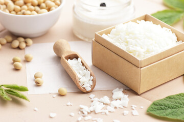 Soy wax with soybeans and fresh plant leaves on natural background, soy candles making and natural cosmetic ingredient  concept