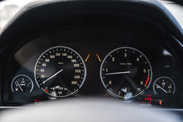 Close up view of a BMW X6 instrument cluster showing speedometer, tachometer, fuel and temperature gauges, and digital display with time and odometer.