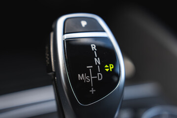 Close up view of the BMW X6 gear selector, featuring a glossy black surface, metallic accents, and illuminated gear position indicators. © Aerial Film Studio