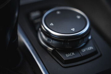 Close up view of the BMW X6 iDrive controller, featuring a circular knob, directional arrows, and buttons, with sleek metallic accents and detailed design. © Aerial Film Studio