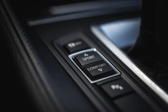 Close up view of the BMW X6 drive mode selector with SPORT and COMFORT buttons, metallic trim, gear shifter, and leather textured surface.