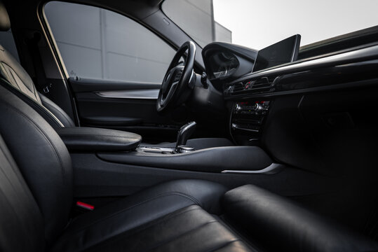 Close up of BMW X6 interior showing black leather seats, sleek center console, gear shifter, and modern dashboard with digital display in soft lighting.