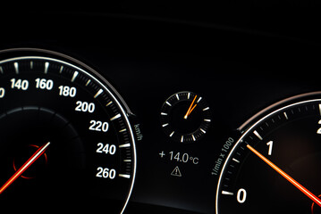 Close up view of the BMW X4 dashboard showing a speedometer, tachometer, analog clock, digital display, and illuminated needles on a black background.