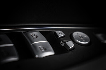 Fototapeta premium Close up view of BMW X4 door controls featuring metallic window and mirror adjustment buttons on a dark textured panel with chrome accents.