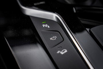 Close up view of the BMW X4 center console, showing buttons for parking assist, camera system, and hill descent control on a sleek black surface. © Aerial Film Studio