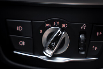 Close up view of the BMW X4 headlight control panel, featuring a rotary dial, lighting symbols, and soft pink illumination on a black and silver design. © Aerial Film Studio
