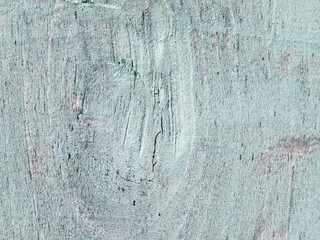 Weathered blue paint peels from an old wooden plank wall, revealing the rough, vintage texture of the timber surface