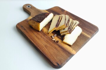Wooden board with sliced cheese on white background. Minimalist food arrangement perfect for culinary, rustic, or lifestyle concepts.