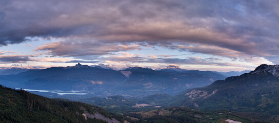 Scenic panorama of rugged peaks and pine forest in British Columbia, Canada, under dramatic clouds.