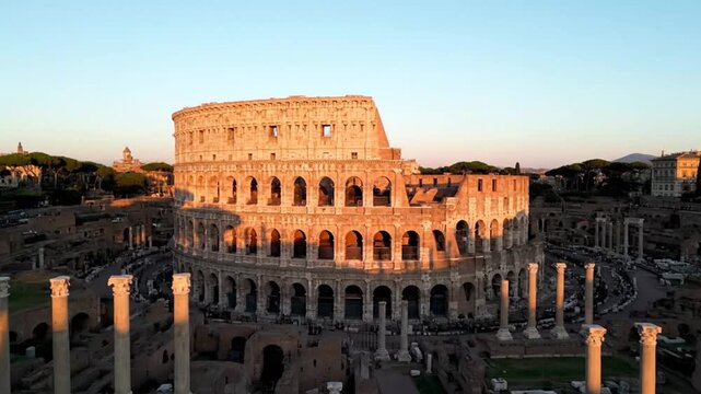 The iconic colosseum in rome, italy, stands tall amidst ancient ruins, bathed in the warm glow of the setting sun, showcasing its grandeur and history