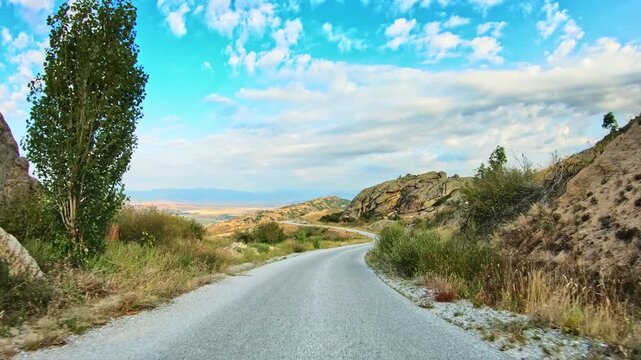 Amazing nature, rocky terrain, dry golden vegetation, fluffy clouds, POV drive