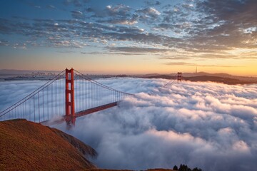 Golden gate bridge towers emerge from sea of fog at sunrise