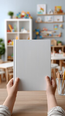 Child's little girl hands hold closed book with a blank front cover in nursery room. childhood and reading concept mockup