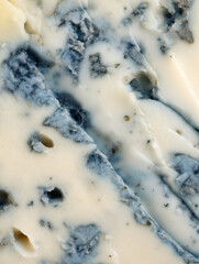Rich blue cheese cut into slices displayed on a wooden board during a gourmet food presentation at a local market