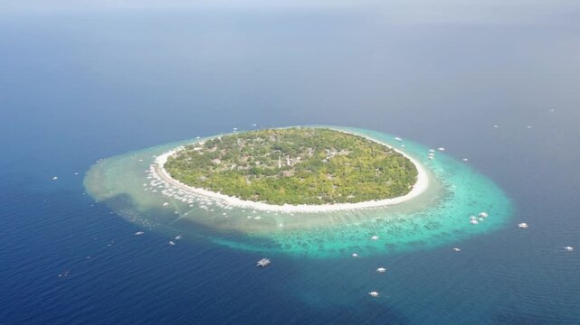 Aerial view of a tropical island surrounded by turquoise water and boats