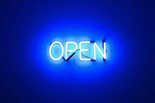 Glowing blue neon "OPEN" sign illuminated against dark wall at night. Electric sign for business, bar, or shop, representing welcome, opening hours, and vibrant nightlife