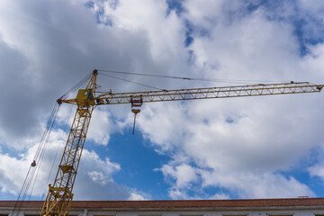 Construction crane against a blue sky. Yellow construction crane.