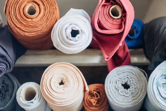 Colorful rolls of fabric in a craft workshop showcase various textures and designs in vibrant hues near the city center