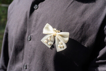 A bow-shaped pin, typically given to wedding guests, attached to a man's shirt.