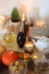 Lit candles, cookies, chocolate, nuts, tea, wine, pumpkins, books, reading glasses and autumn leaves on the table. Autumnal hygge at home. Selective focus.