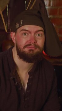 Bartender puts down root to meet guest in pub. Servile bartender dwarf takes order for drink and food from visitor in tavern. Medieval life scene