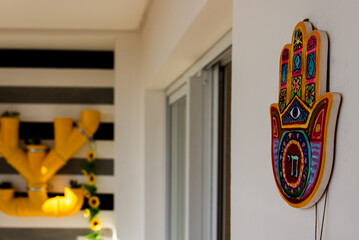 White balcony with a colorful mandala hanging on the wall and yellow plants in the background.