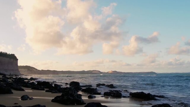 Fluffy white clouds drift lazily across a serene, clear blue sky