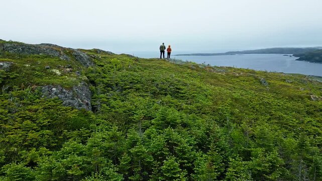 Couple of hikers overlook Savage Cove and Cr&eacute;maill&egrave;re Harbor near St. Anthony, Newfoundland CA.