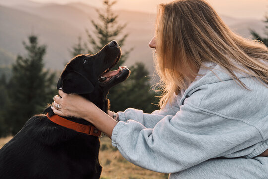 A loving moment shared between a woman and her black Labrador Retriever in a scenic outdoor setting. Showcasing companionship and the bond between humans and animals.