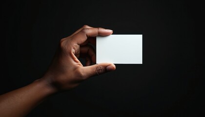 Hand holds blank white business card against dark background. Pro presentation, marketing, networking tool. Use for contact details, corporate identity, graphic design template.