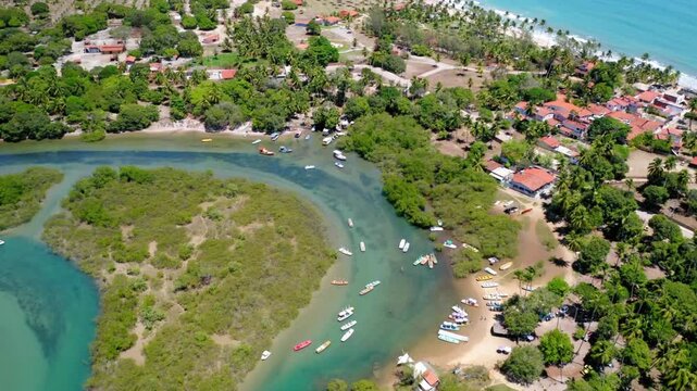 Aerial view of a tropical river meeting the ocean near a coastal village