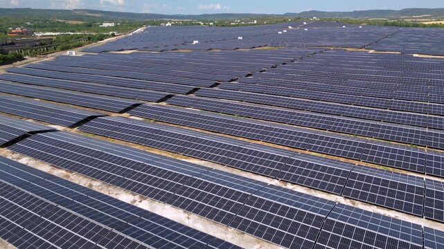 Drone view of expansive photovoltaic solar panel installation in rural agricultural area, renewable electricity generation plant supplying sustainable green energy for environmental protection and cli