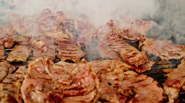 A gloved hand prepares carne asada on a smoking grill