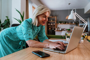 Smiling senior freelancer working remotely from home office