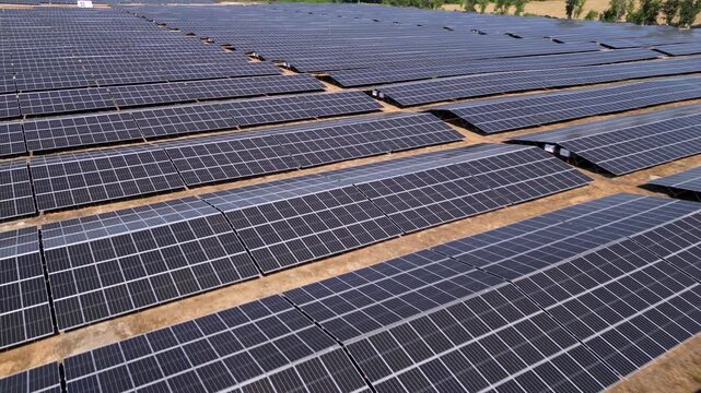 Drone view of expansive photovoltaic solar panel installation in rural agricultural area, renewable electricity generation plant supplying sustainable green energy for environmental protection and cli