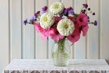 Colorful bouquet of zinnias, pink lavatera and ageratum in clear vase
