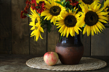 Sunflowers bouquet in rustic vase with apple