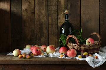 Rustic autumn still life with  bottle. harvest of garden apples and plums.
