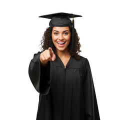Joyful young woman wearing graduation cap and gown pointing forward with a smile isolated on transparent background