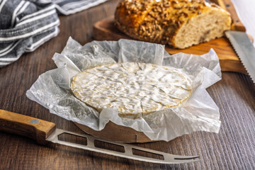 Camembert cheese on wrapping paper. French cheese with mold on the surface.