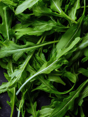 Fototapeta premium Fresh arugula leaves arranged on a dark surface, showcasing vibrant greens perfect for salads and garnishes in culinary dishes