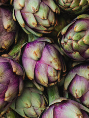 Fototapeta premium Fresh artichokes arranged beautifully showcasing their rich purple and green colors in a farmers market display during spring season