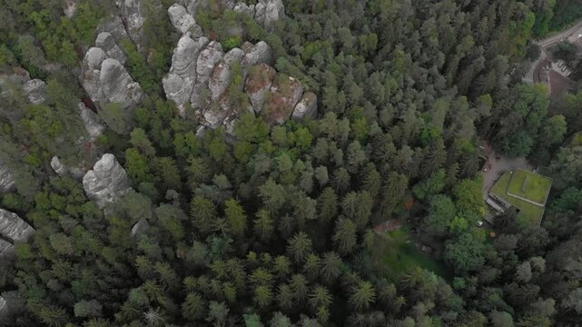 Aerial view of a forest with rock formations and a building with a green roof