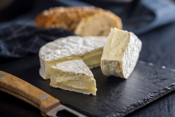 Camembert cheese on black table. French cheese with mold on the surface.